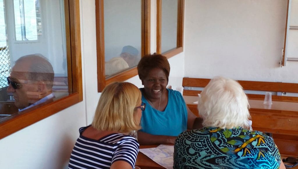 Tre kvinner som har en hyggelig samtale ved et trebord i et lyst rom ombord på S/S Storskär i Stockholms skjærgård sommeren 2014.