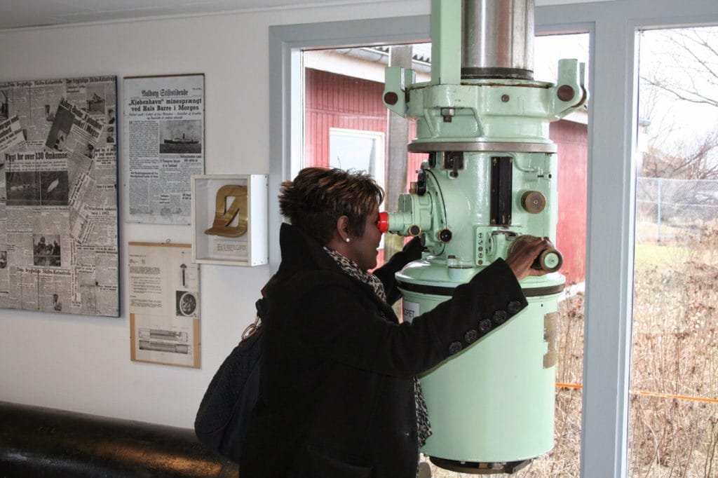 Person som ser gjennom et stort, vintage teleskop i et museumsrom.