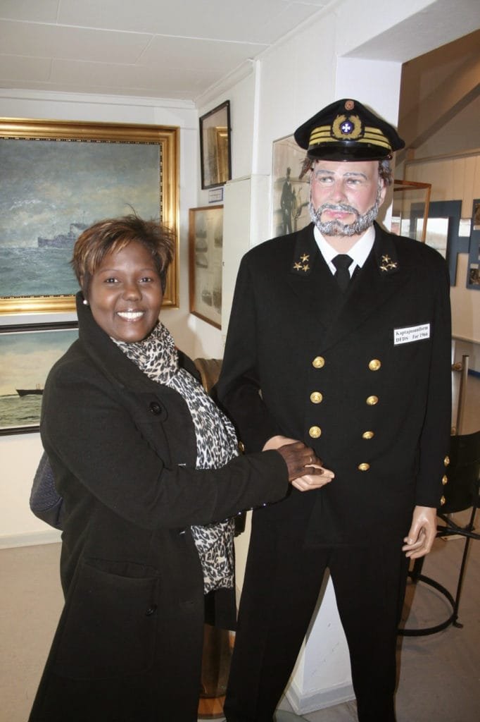 En kvinne som håndhilser på en mann kledd i sjøkoffiseruniform inne i et maritimt museum.