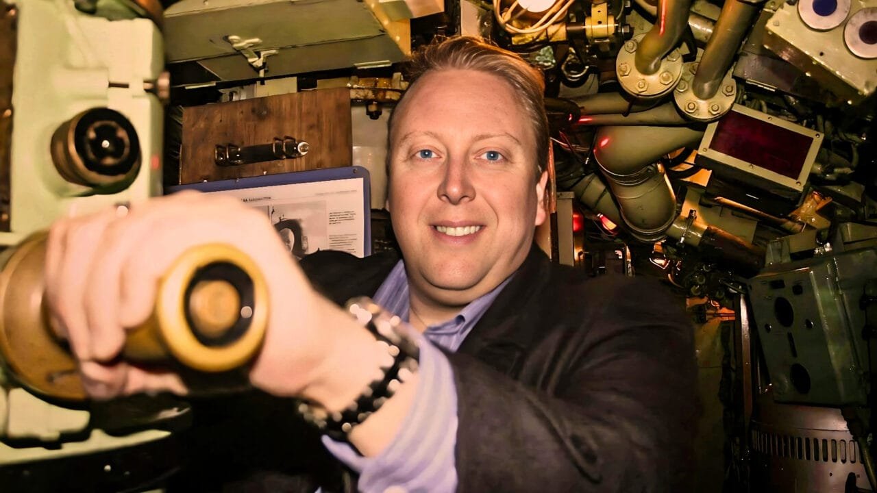 Mann som betjener periskop inne i ubåtens kontrollrom.